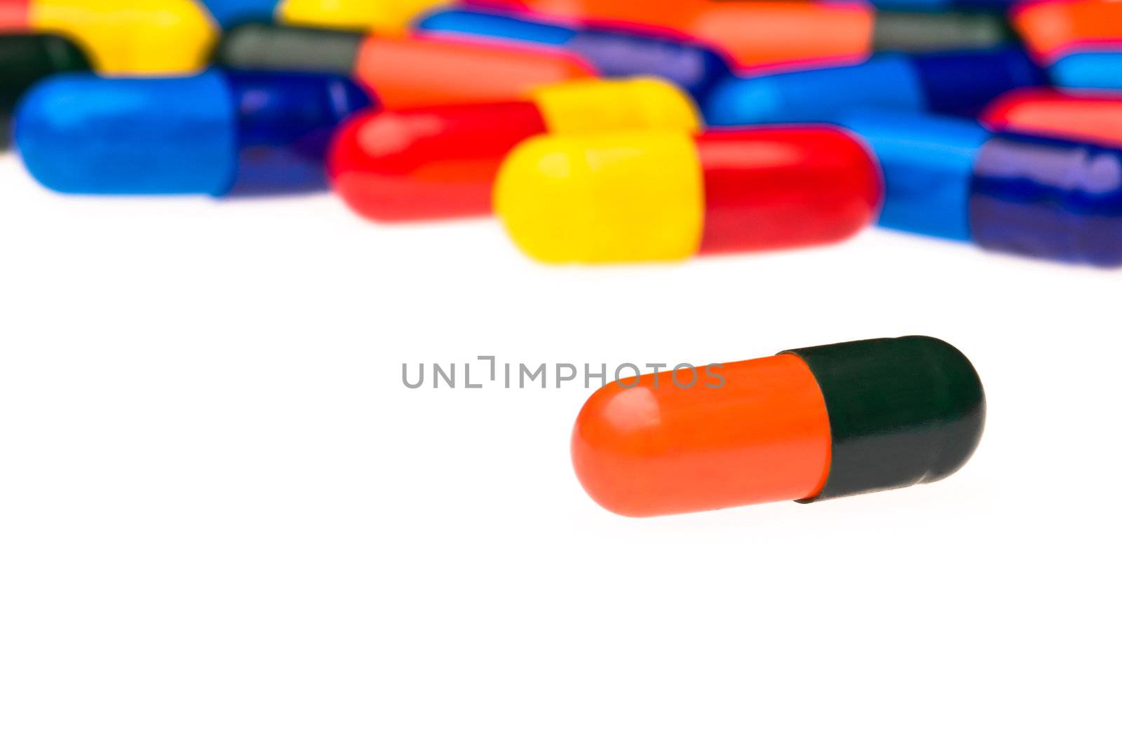 One orange black capsule in front of many colorful, blurry in the background