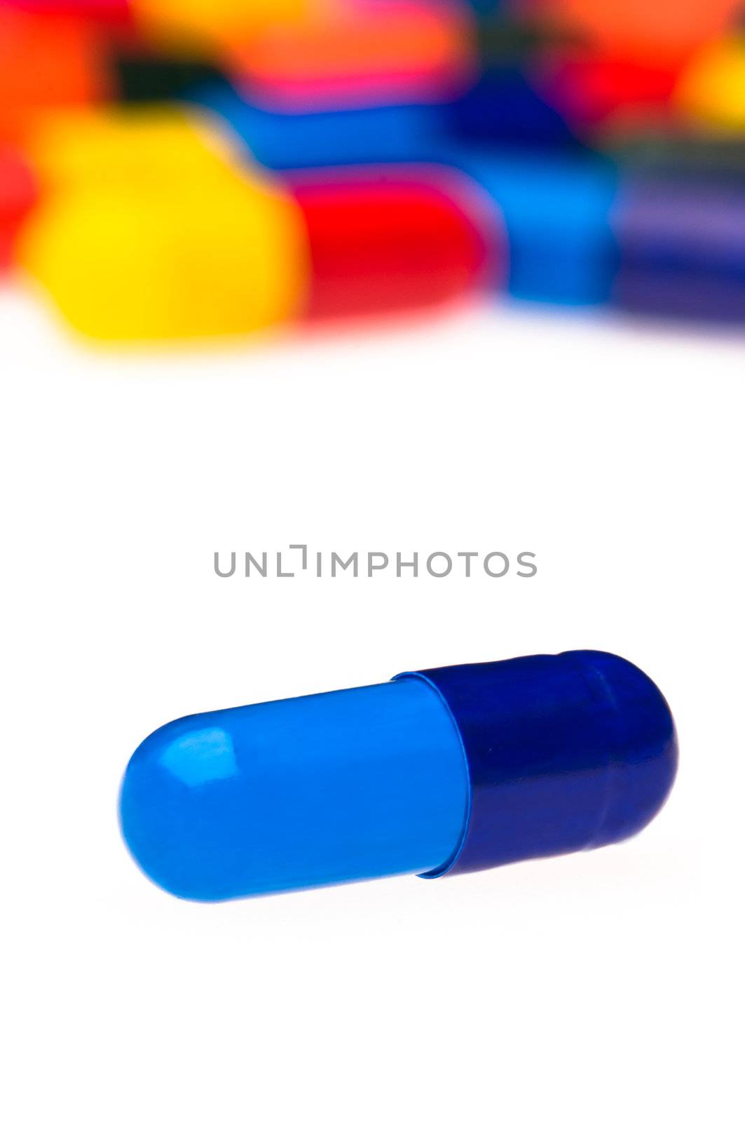 One blue capsule in front of many colorful, blurry in the background