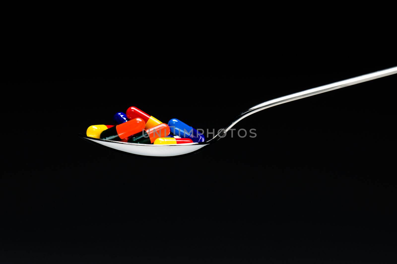 One spoon of medication in front of a black background