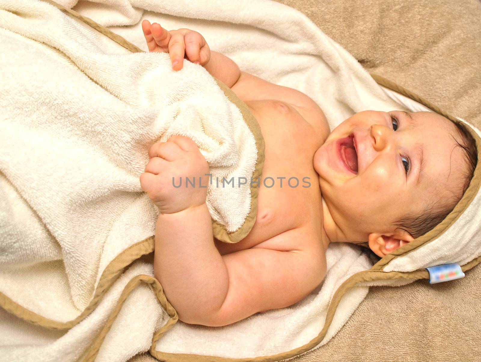 Laughing baby laying on it's back, in a towel