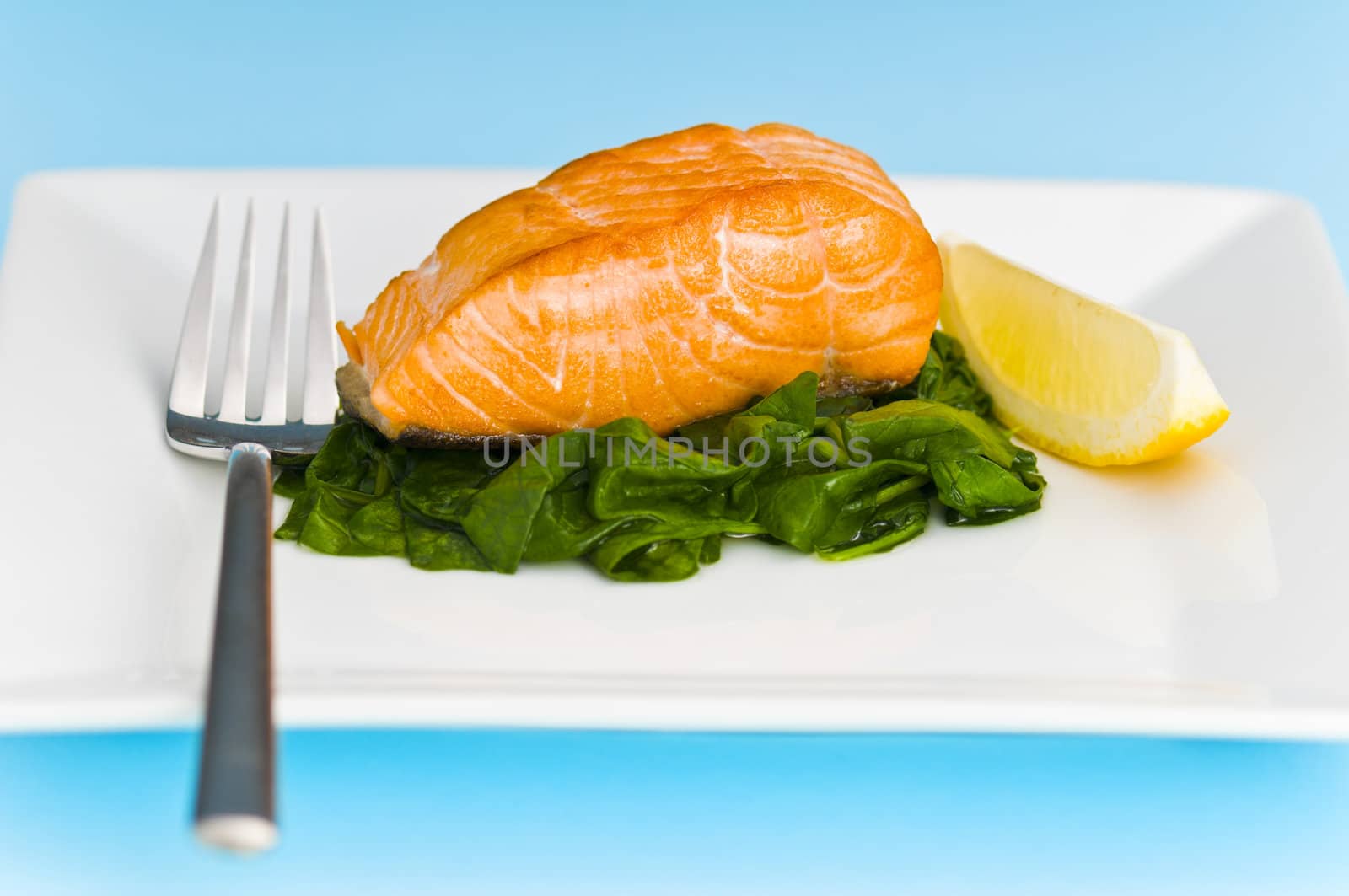 Salmon steak on spinach, decorated with lemon and fork