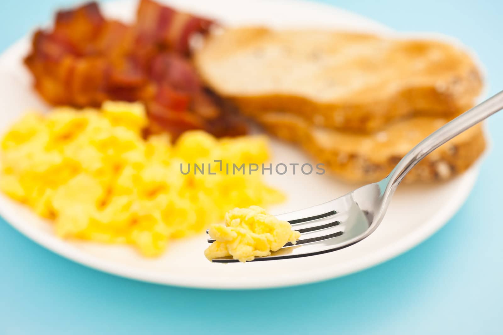 American breakfast, bacon and scrambled egg, fork lifts egg