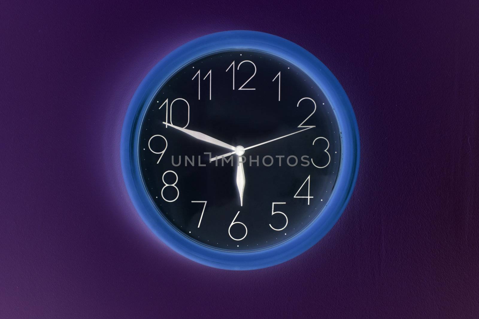 Shaded clock hanging on wall and showing time