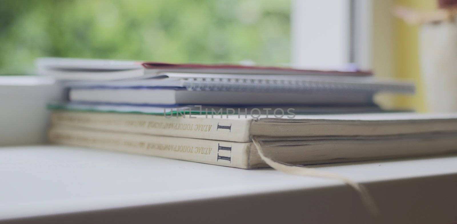 Few books and notebooks laying on window ledge