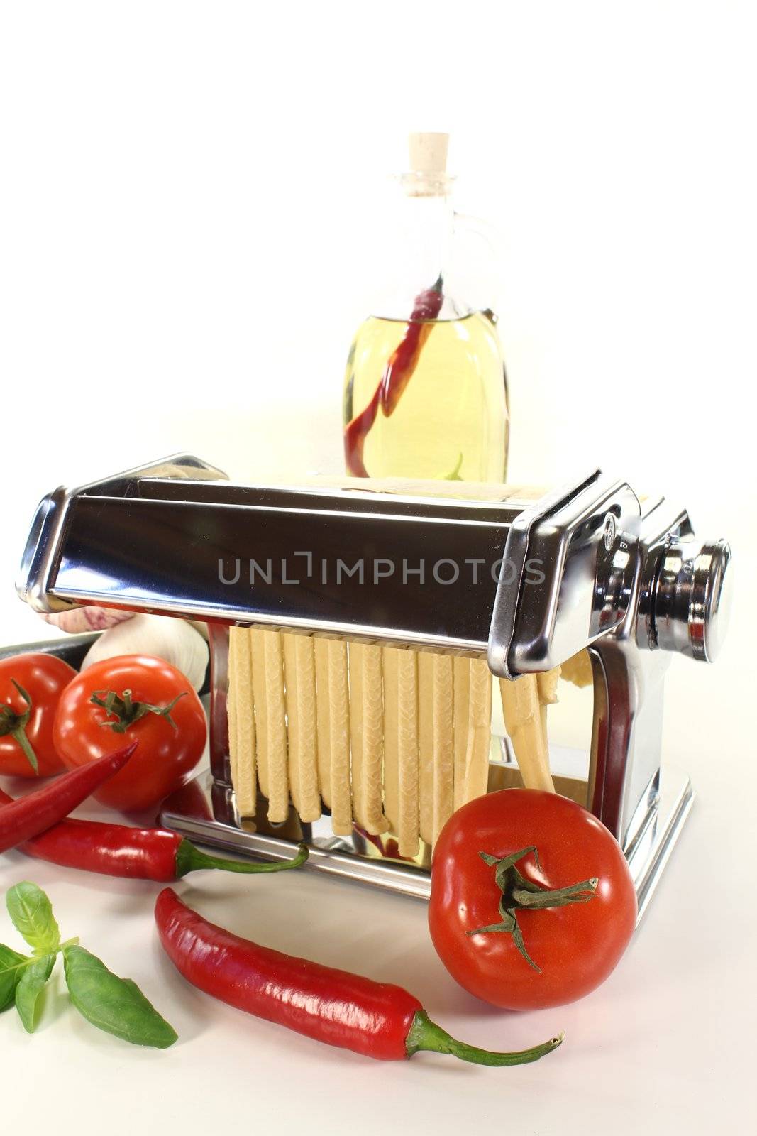 tagliatelle in a pasta machine with tomatoes, cheese and basil