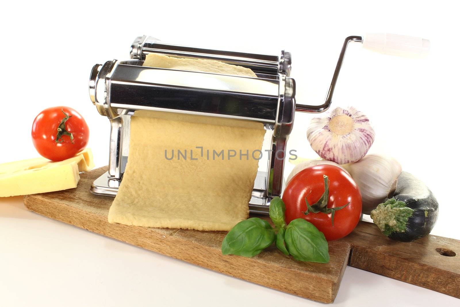 Noodle dough in a pasta machine with tomatoes, garlic and basil