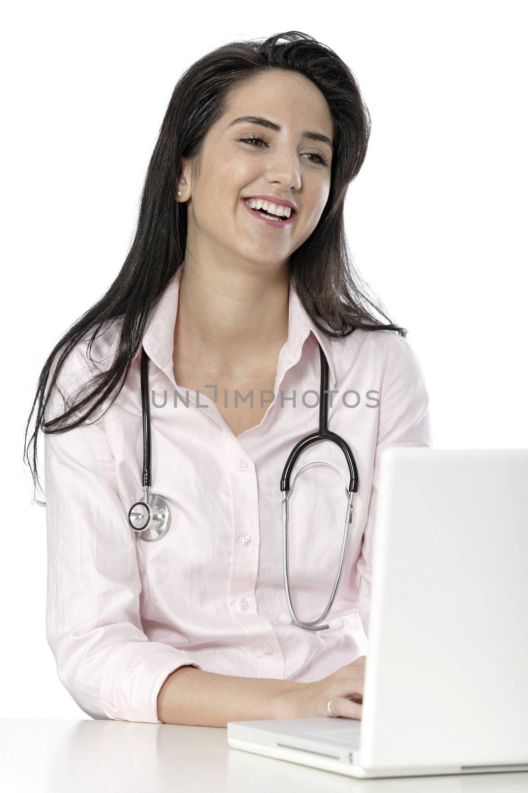 Beautiful young doctor sat smiling at her work desk using her computer.