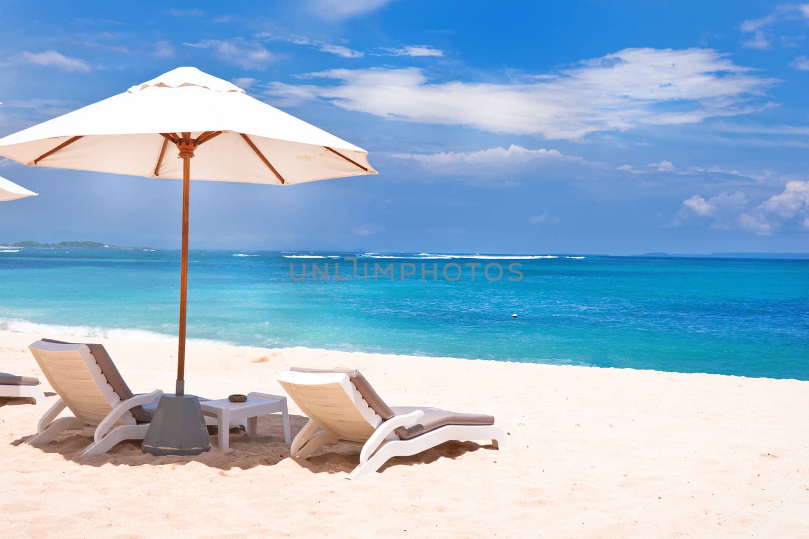 Tranquil beach scene with umbrella and lounge chairs