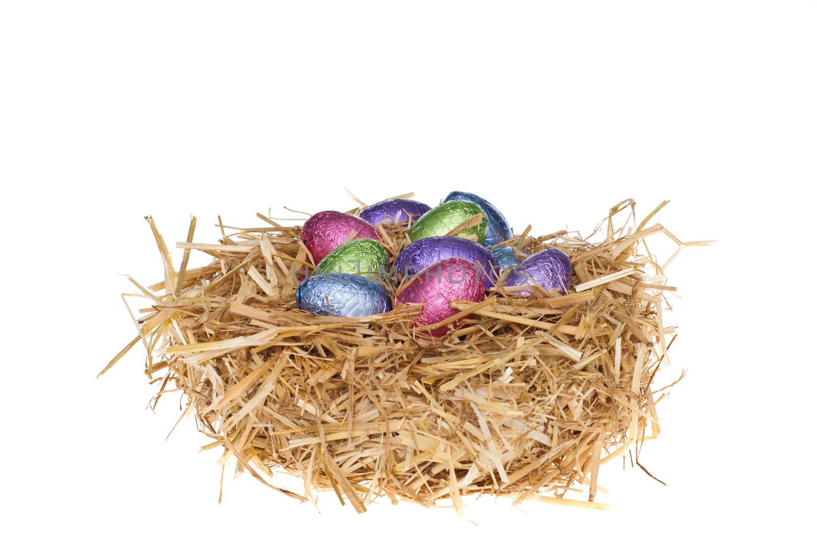 Straw nest with chocolate Easter eggs over white studio shoot