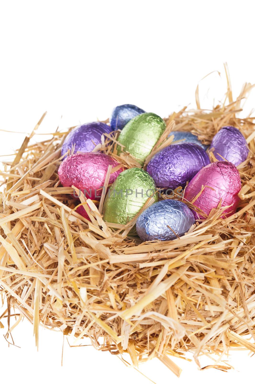 Straw nest with chocolate Easter eggs over white studio shoot