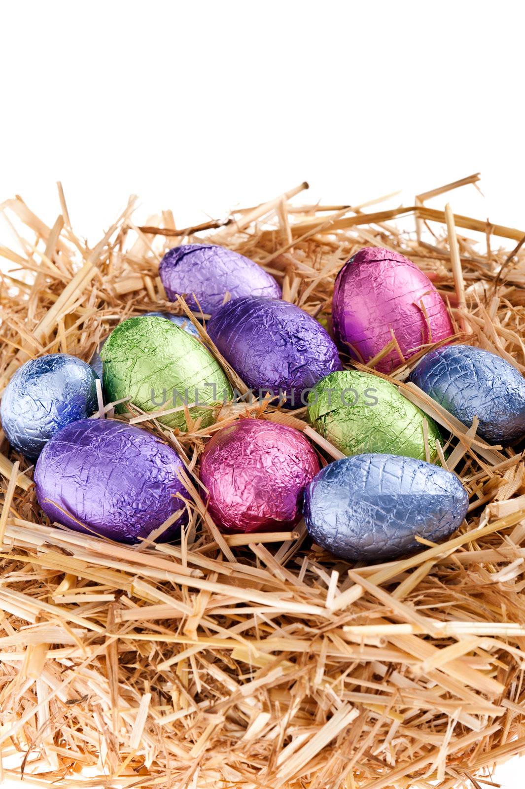 Straw nest with chocolate Easter eggs over white studio shoot