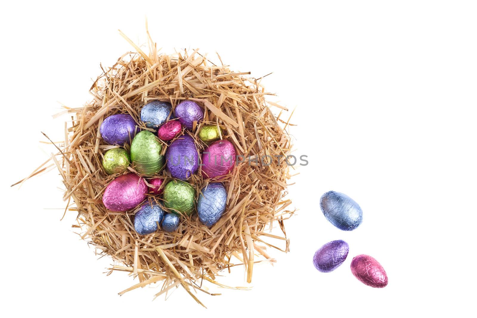 Straw nest with chocolate Easter eggs over white studio shoot