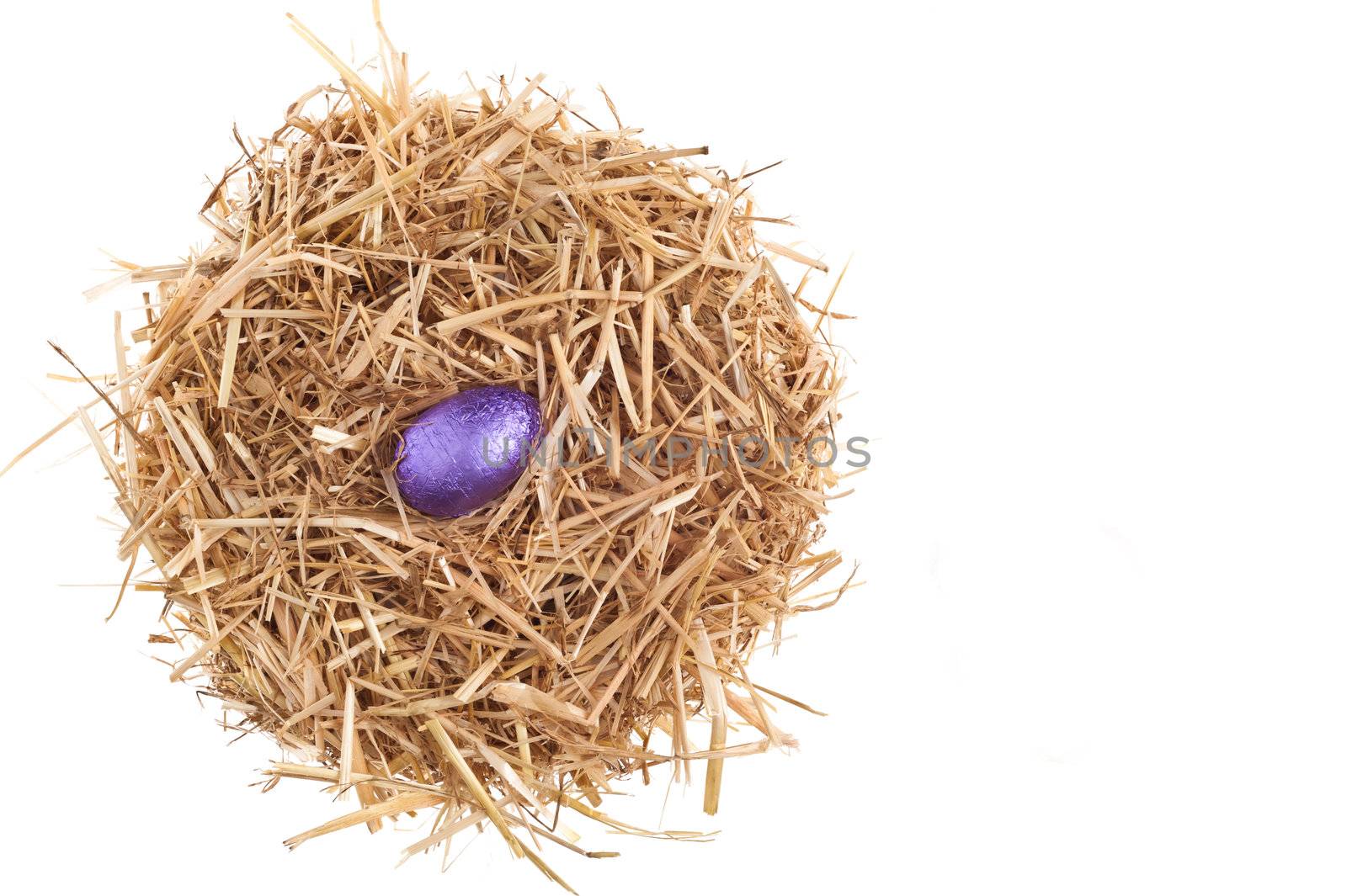 Straw nest with chocolate Easter eggs over white studio shoot