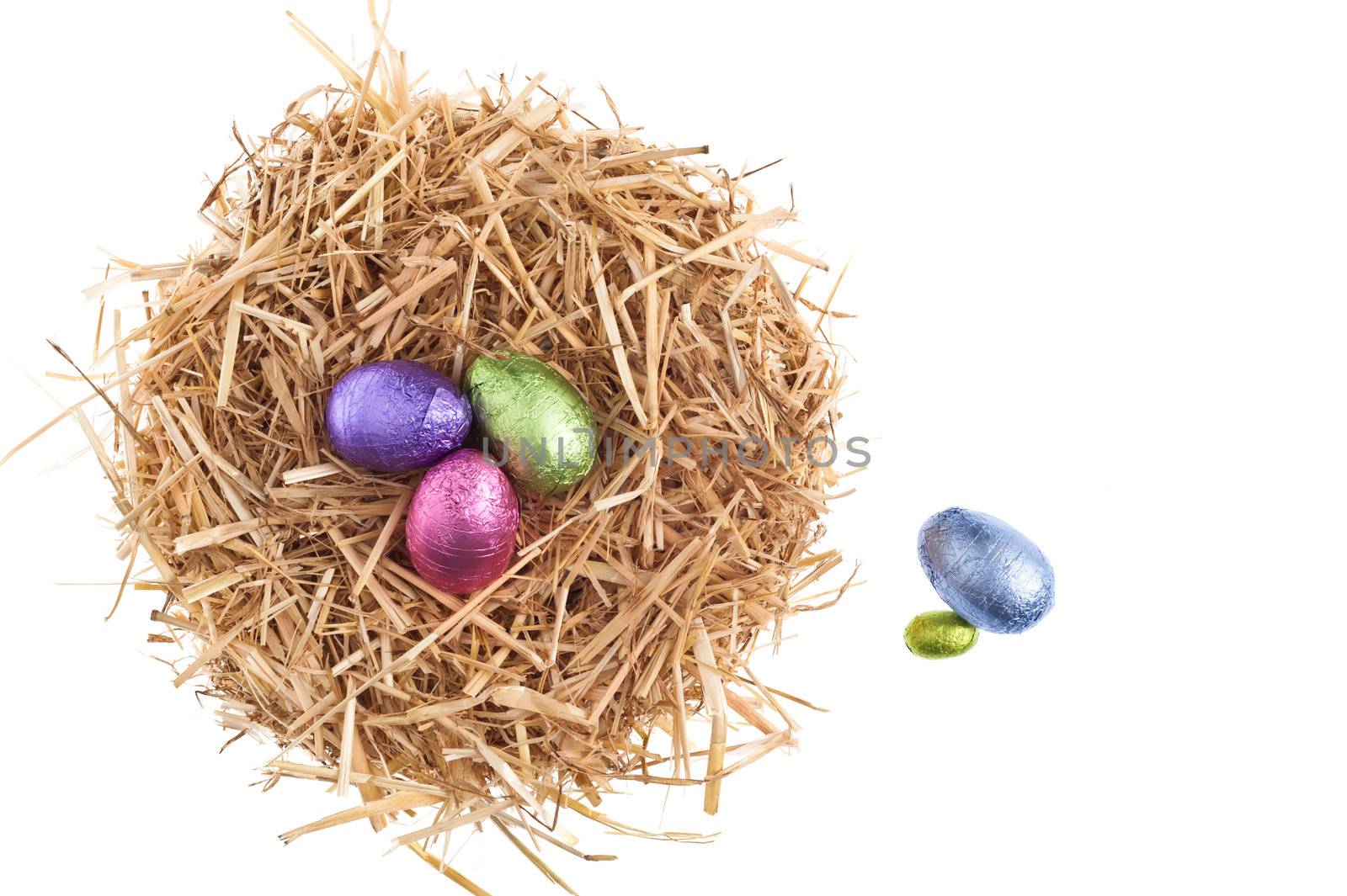 Straw nest with chocolate Easter eggs over white studio shoot