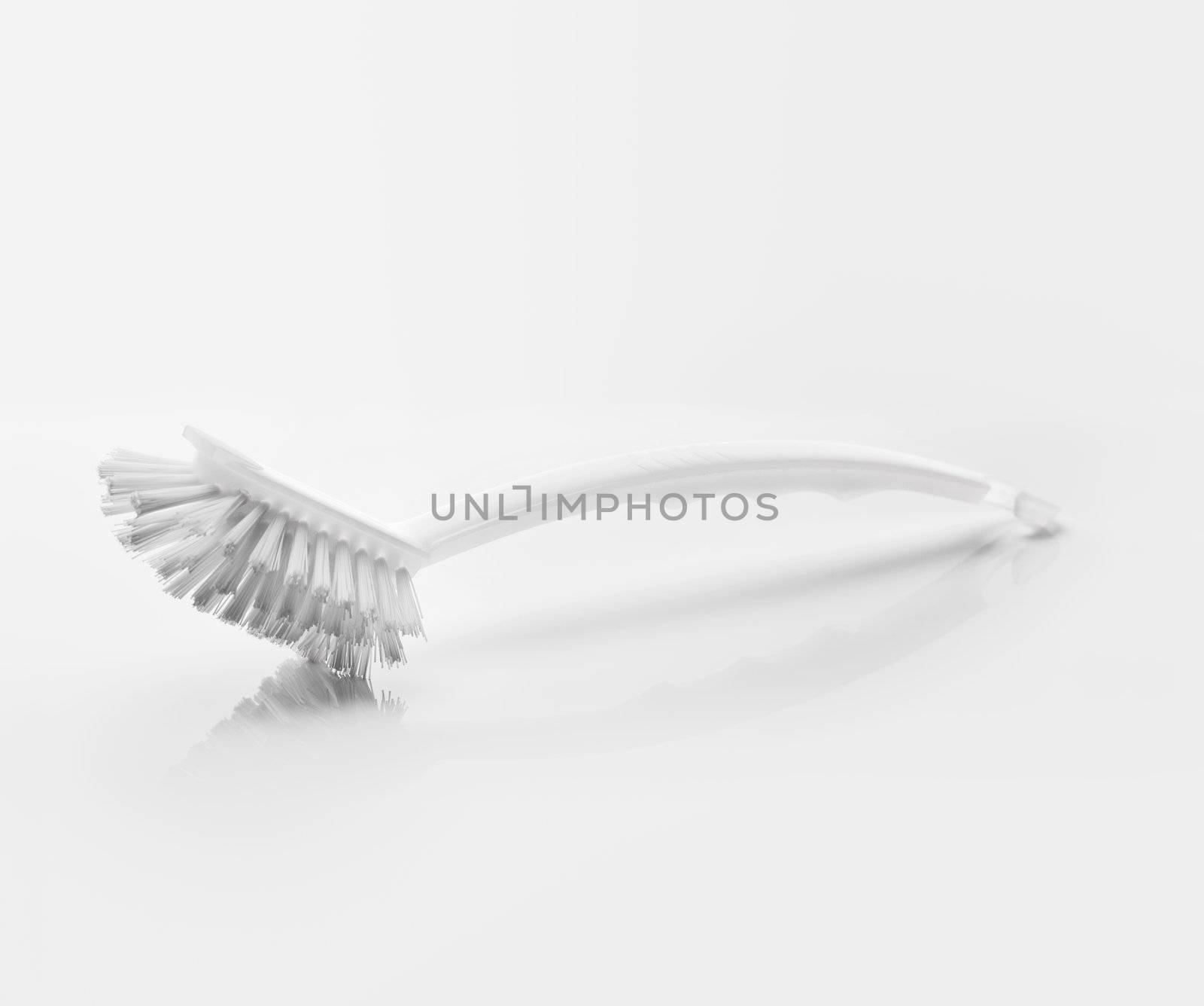 A White clean new dish brush on light grey reflective background.