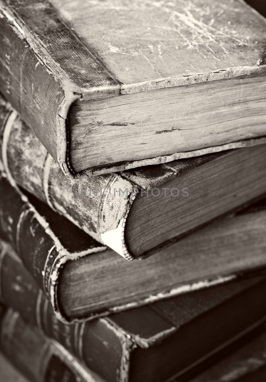 Sepia toned image of a stack of old worn books.