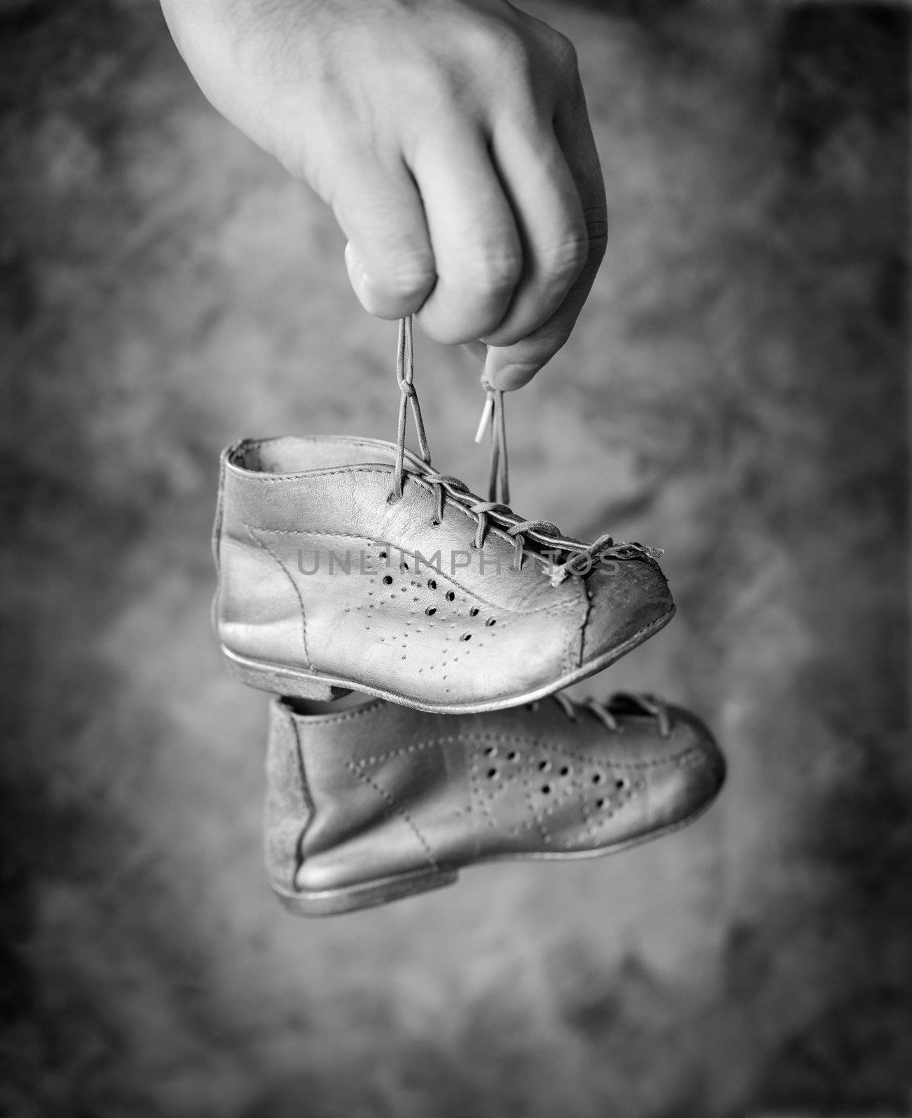 Black and white image of Man holding his old baby shoes in his hand.