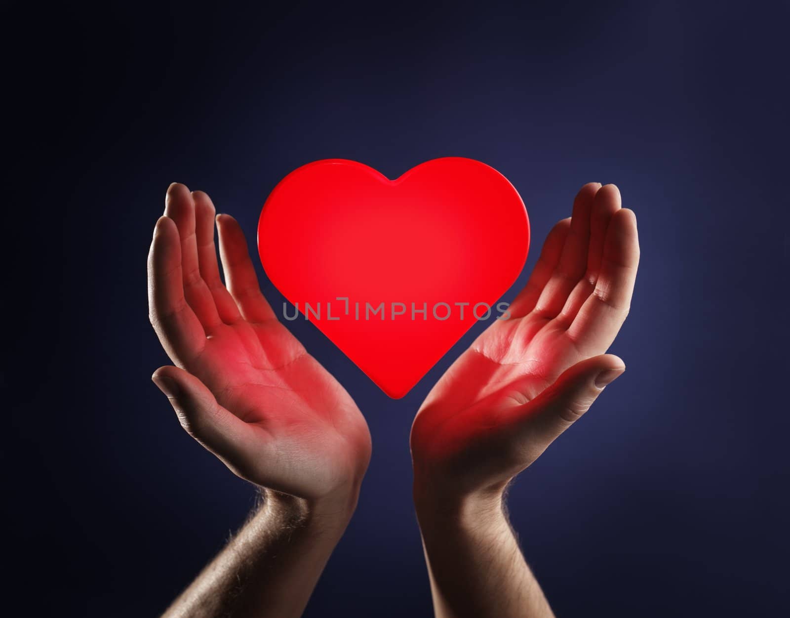 Hands of a man and a red glowing heart.