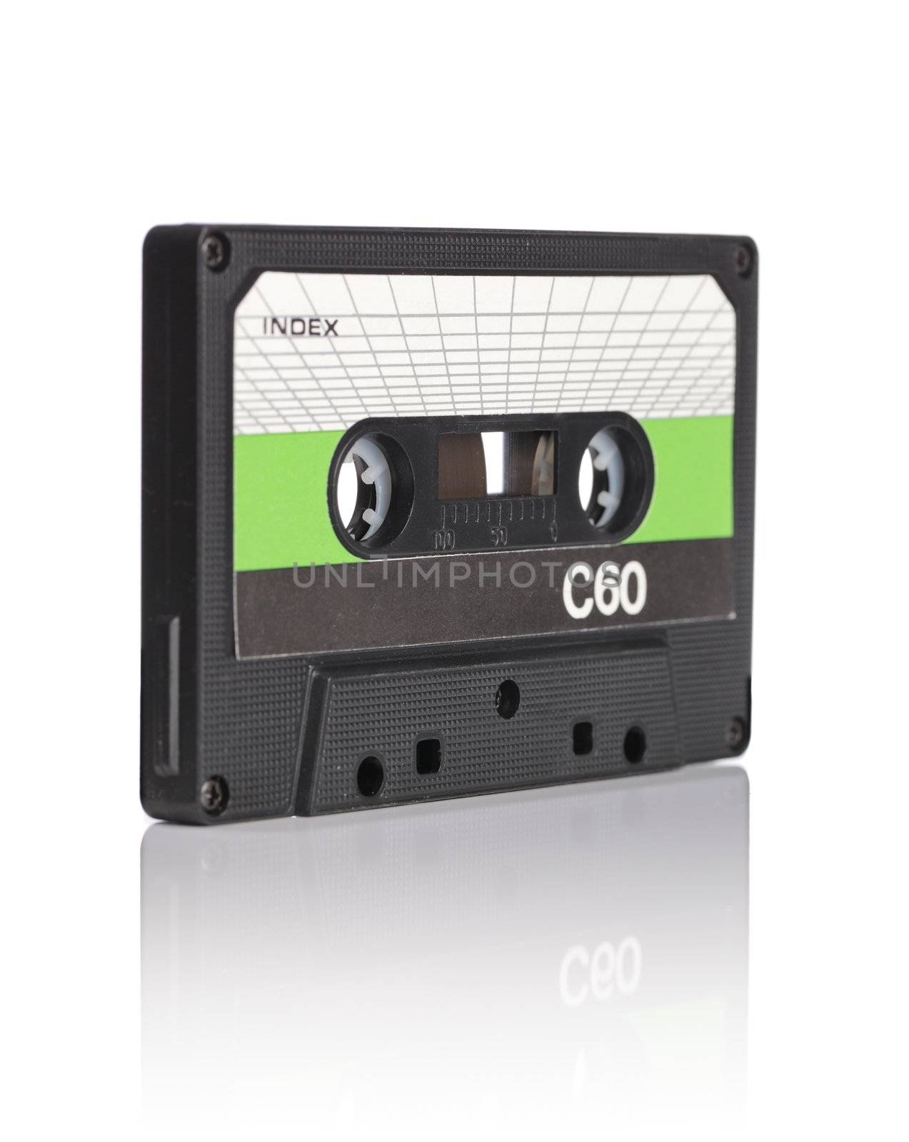 Old compact audio cassette on reflective white background. Very short depth-of-field.