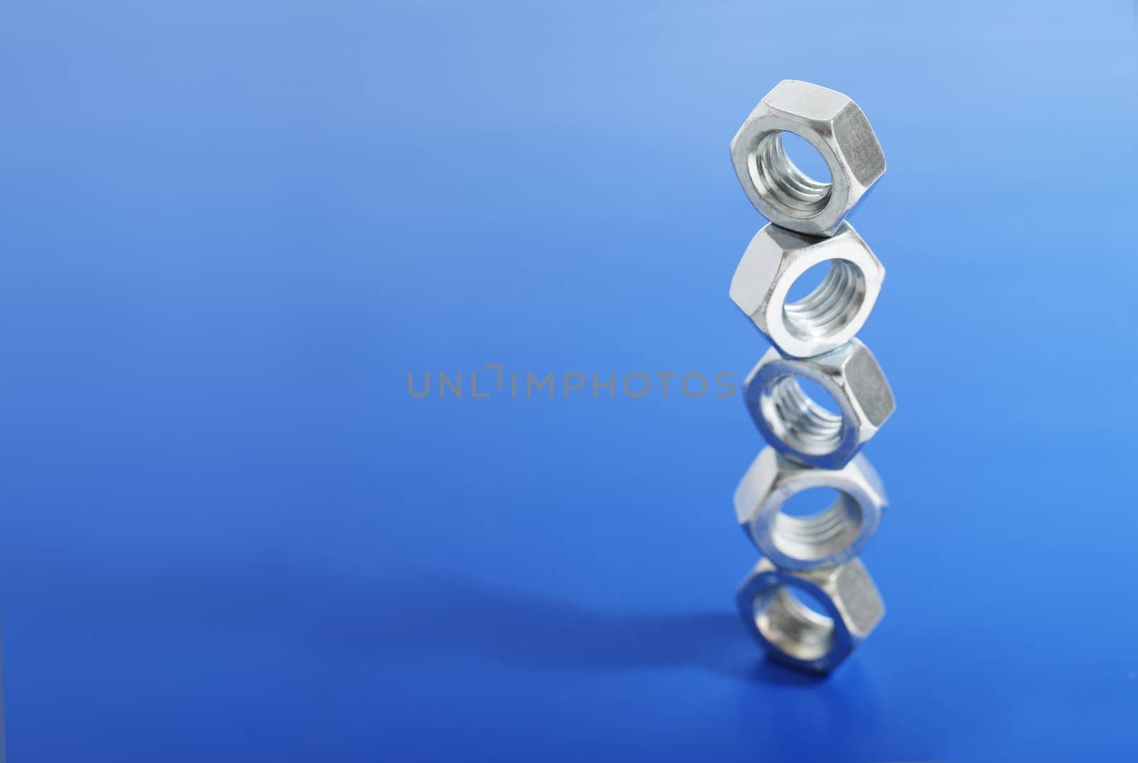 Steel nuts stacked on blue background.