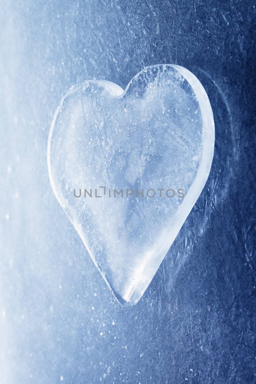 A Heart-shaped piece of ice on ice background.