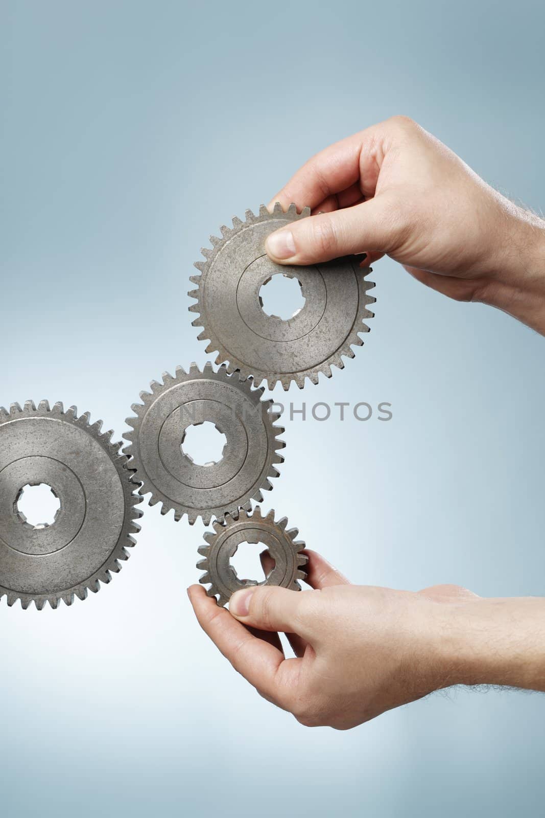 Man designing a mechanic system with old metallic cog gear wheels.