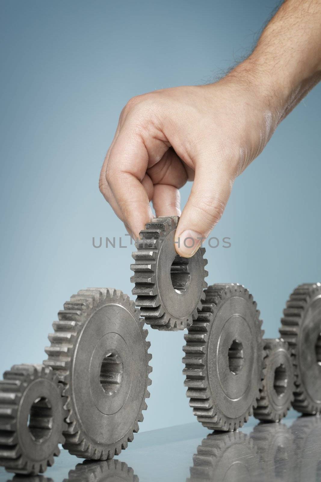 Man adding a cog gear wheel into a row of old cogs.