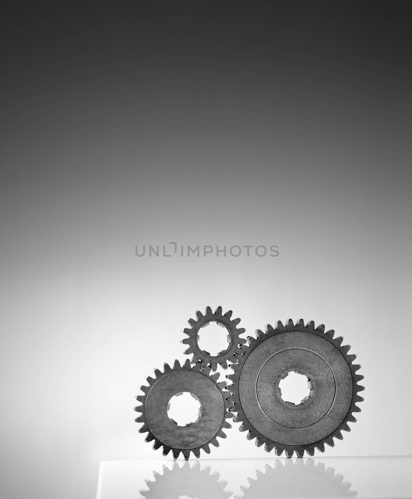 Black and white photograph of three old cog gear wheels.