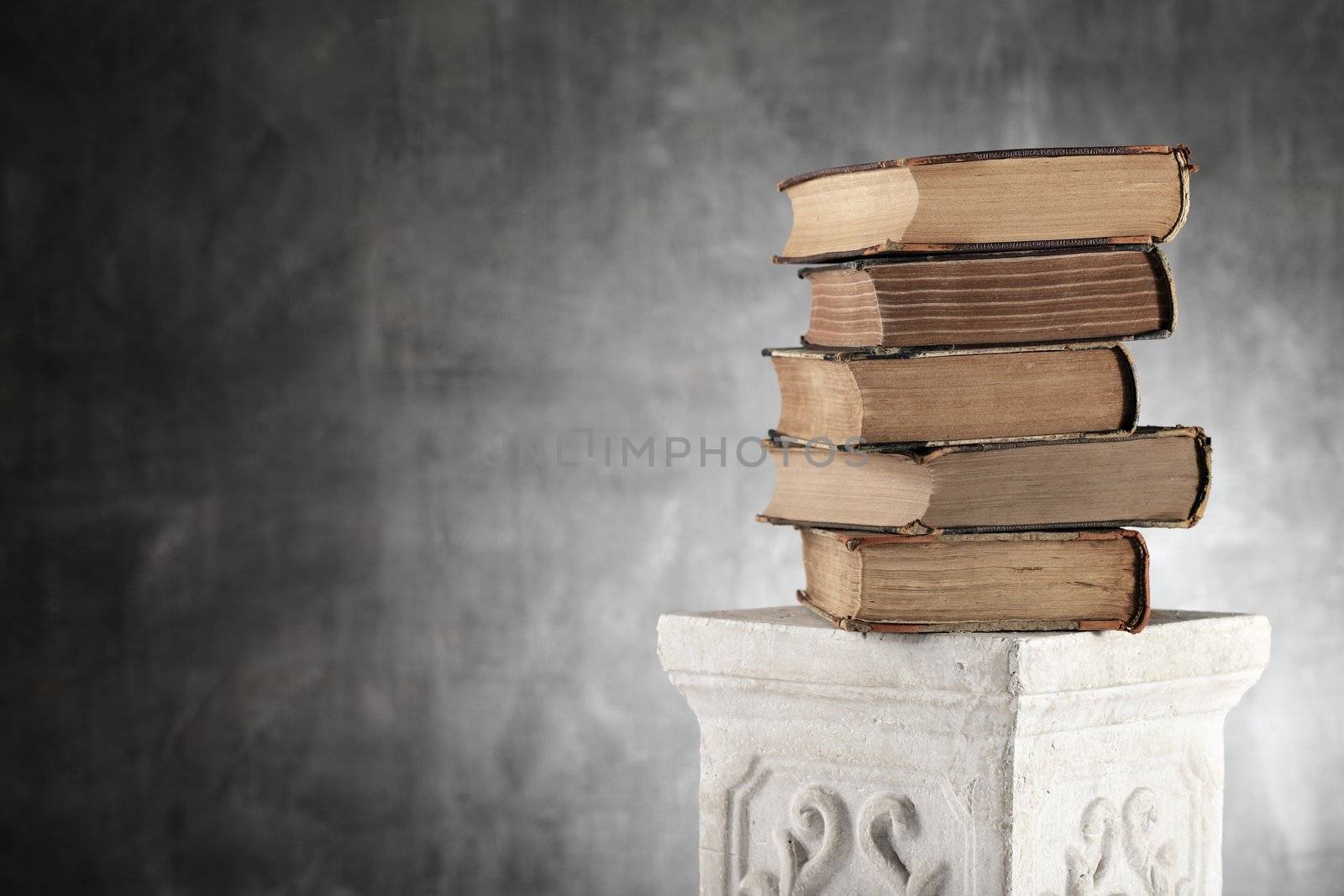 Stack of antique yellowed books on a plaster column.