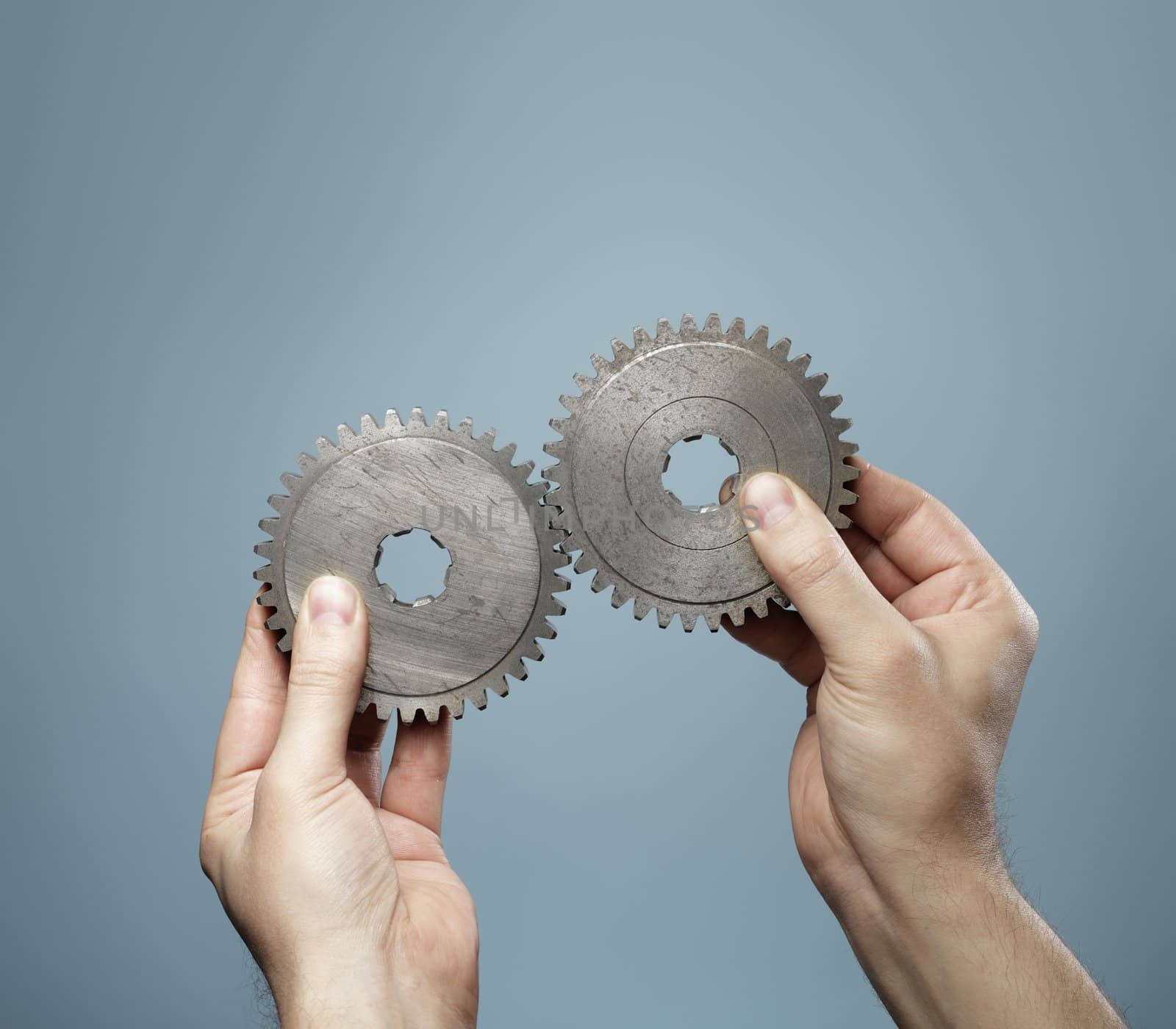 A Man holding a matching pair of old cog gear wheels in his hands.