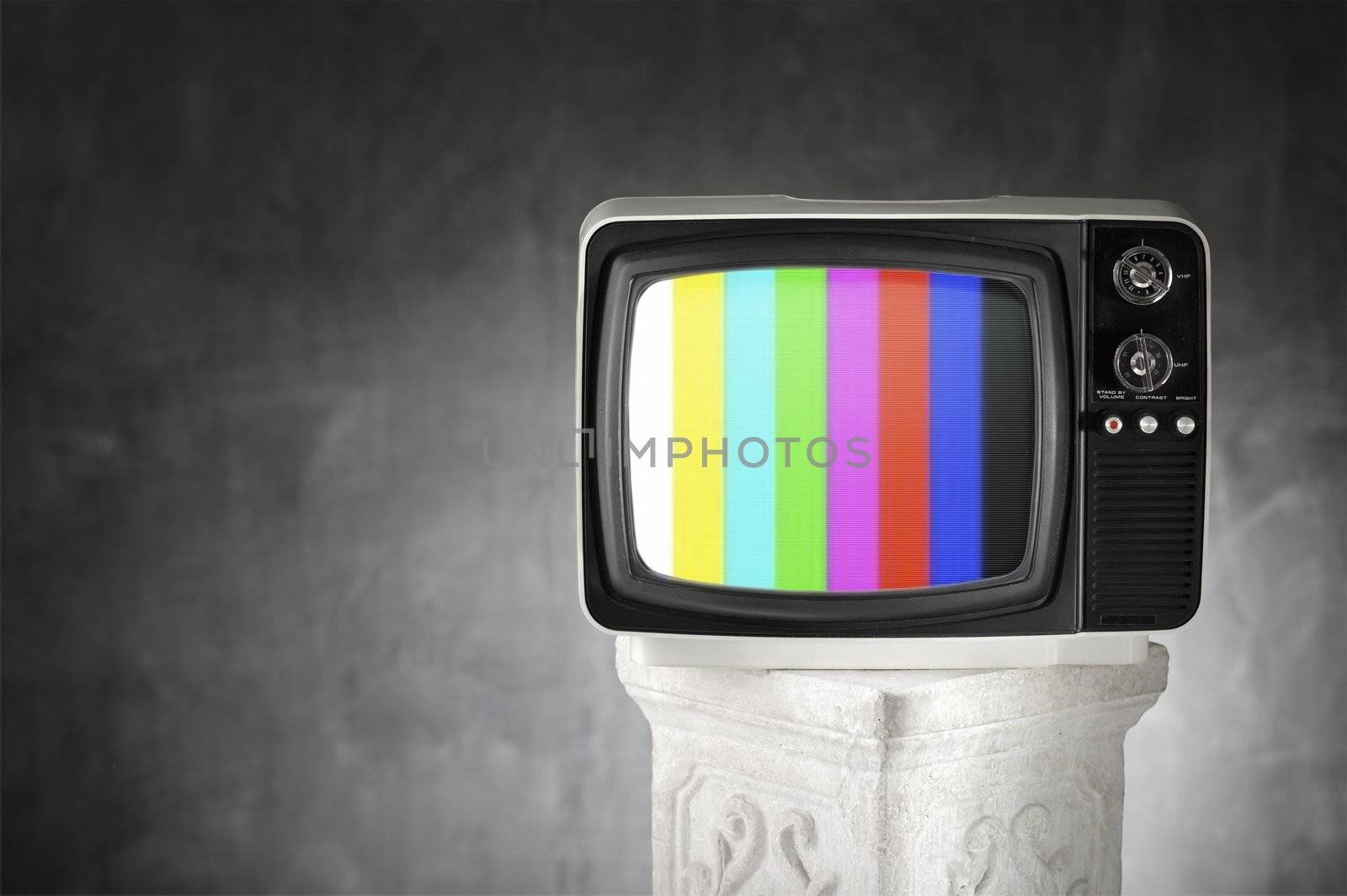 Old television with color bars on a plaster column.