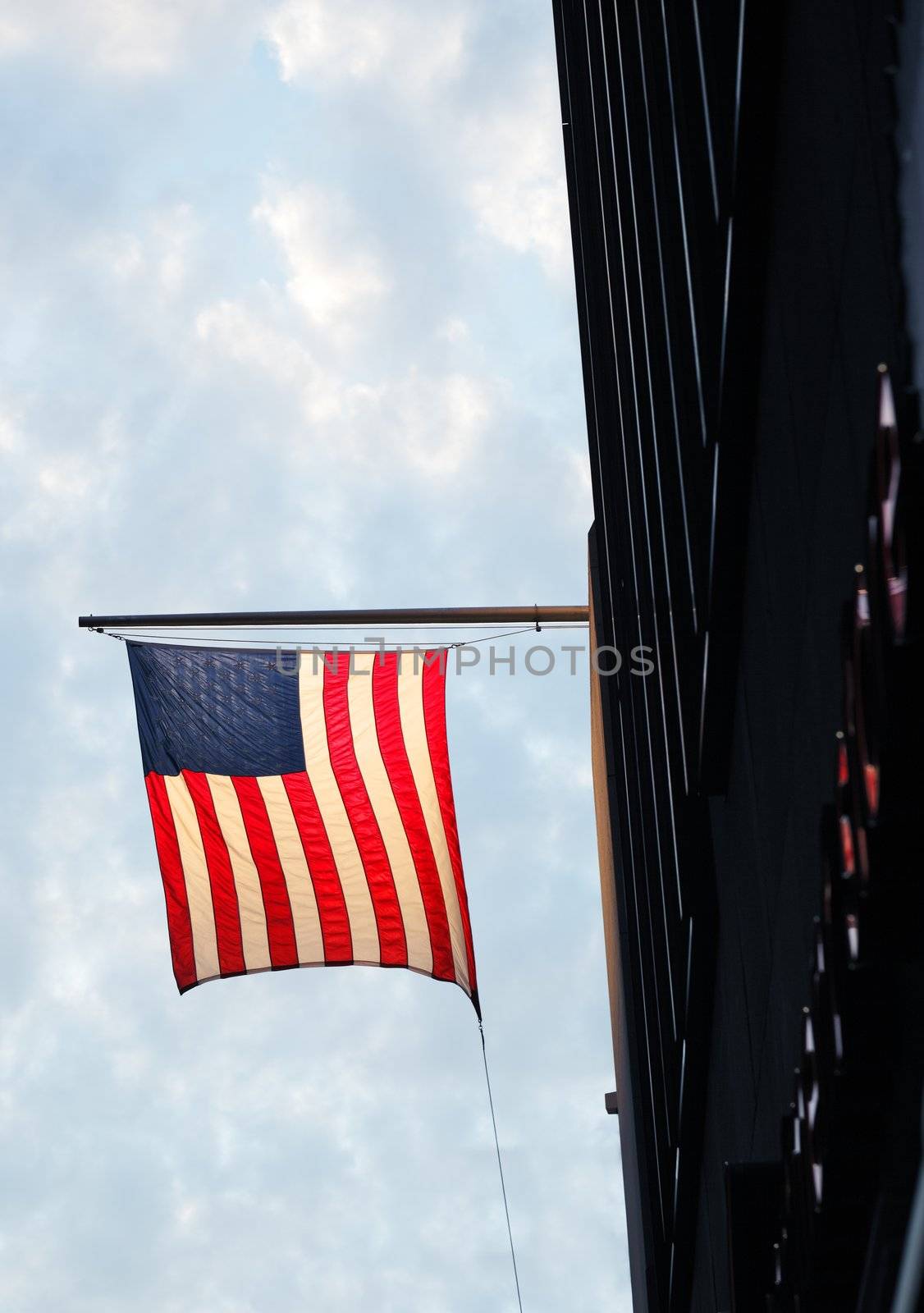 The Flag of United States in evening light, hanging from a building wall.