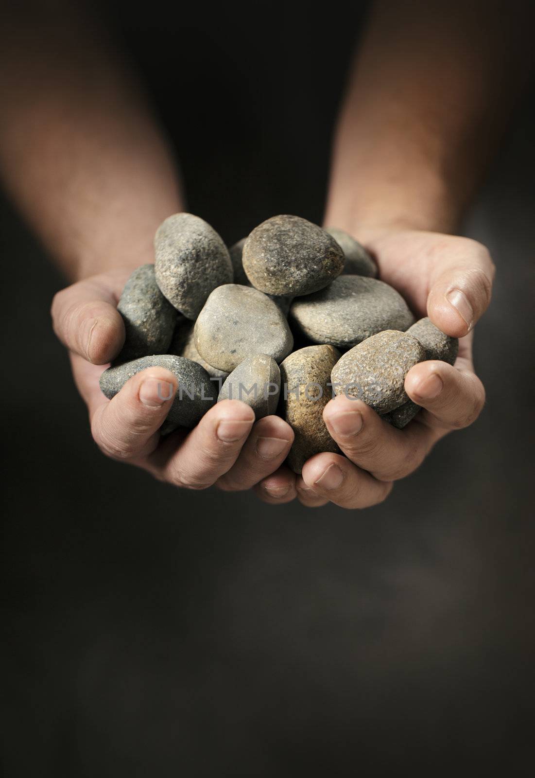 Man holding small rock pebbles in his cupped hands.