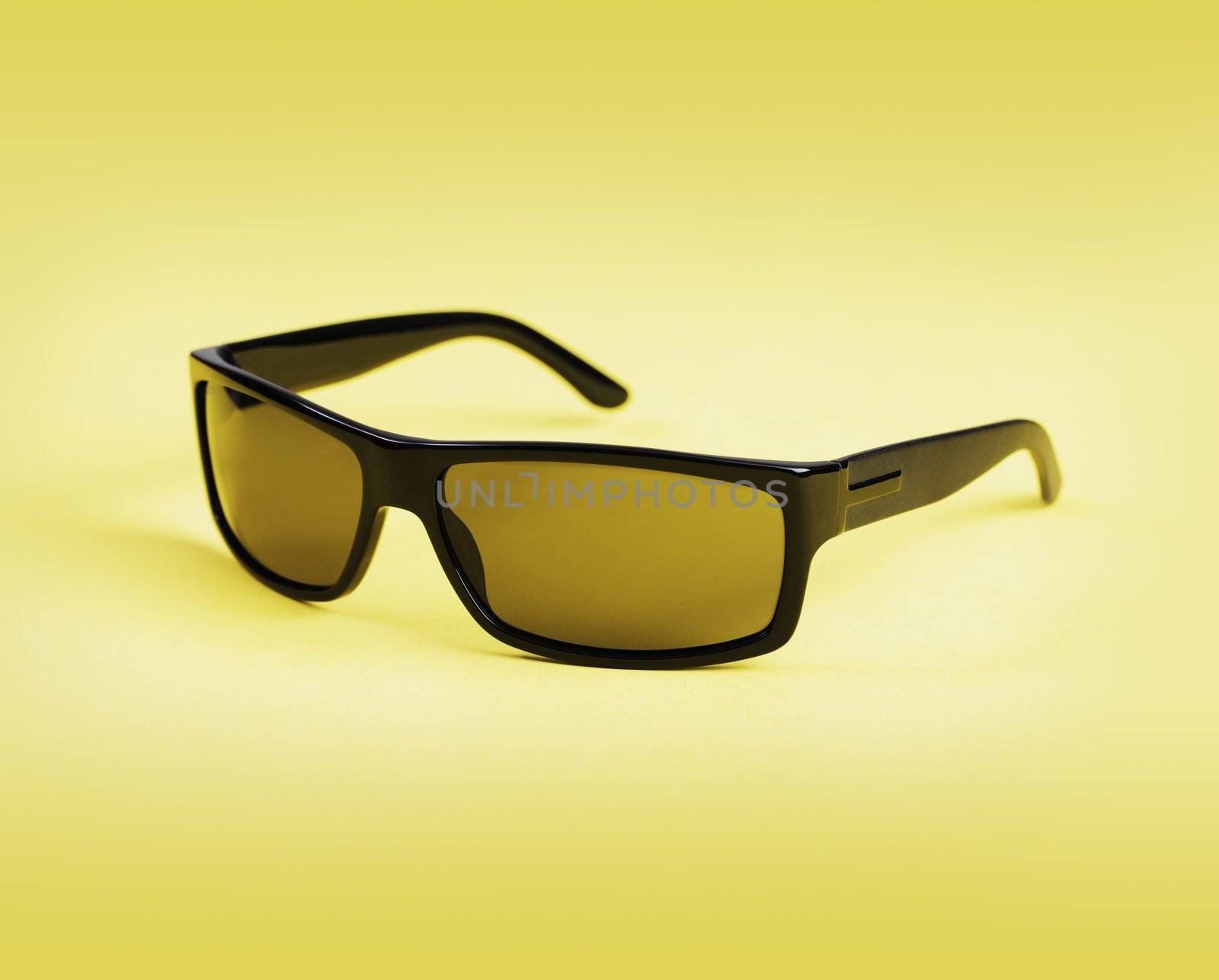 Quality men's sunglasses on yellow background.
