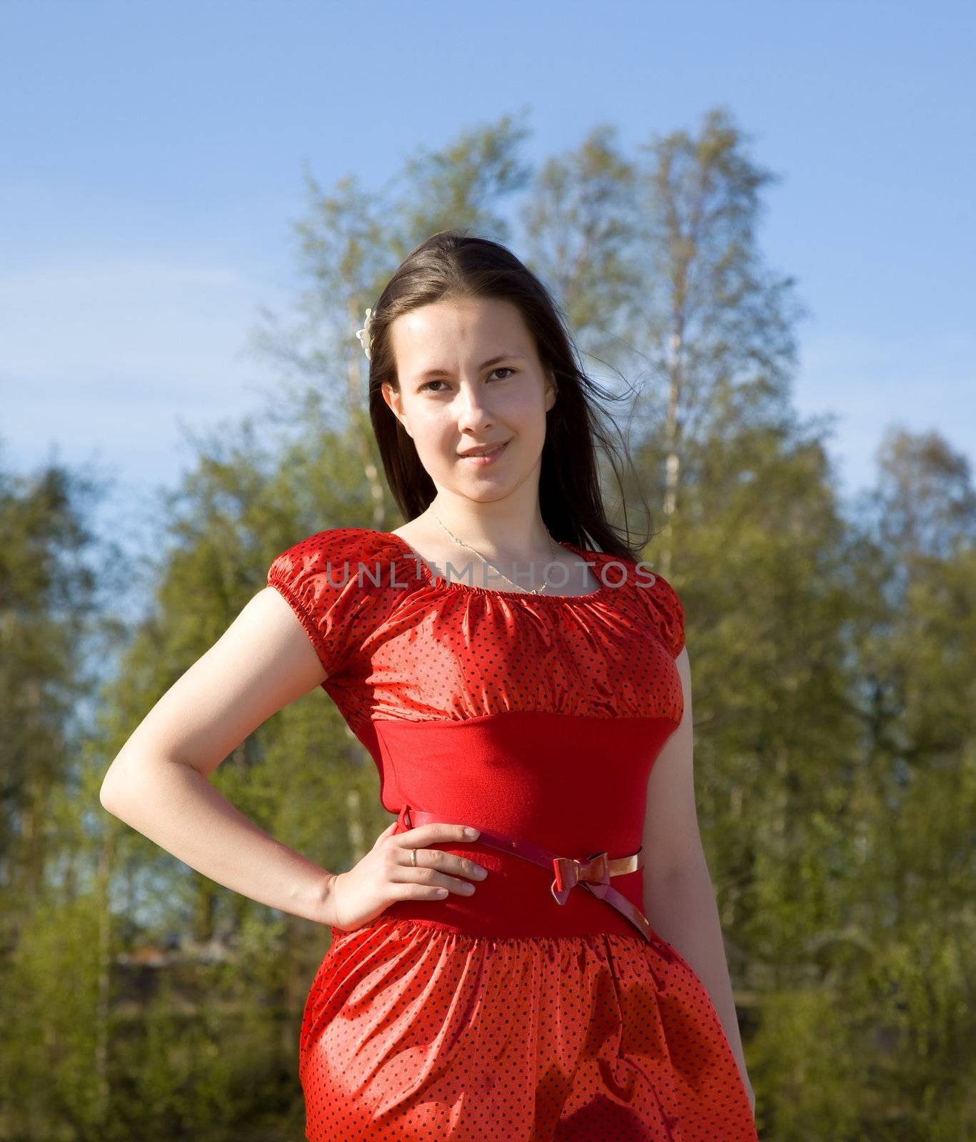 
portrait of a beautiful girl in a red dress with her hair in the background of green foliage
