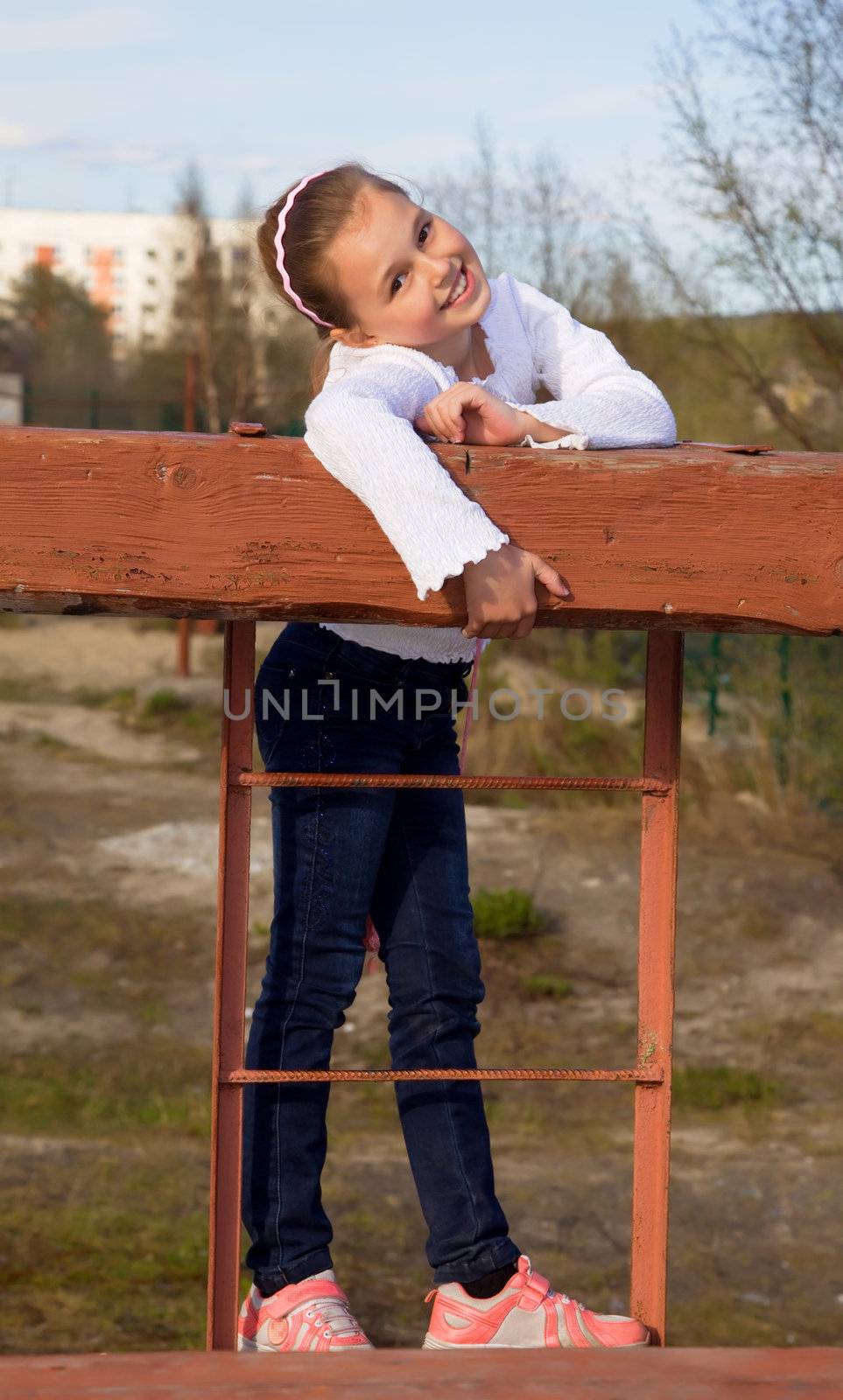 A girl in jeans and sneakers to the playground in sunlight.