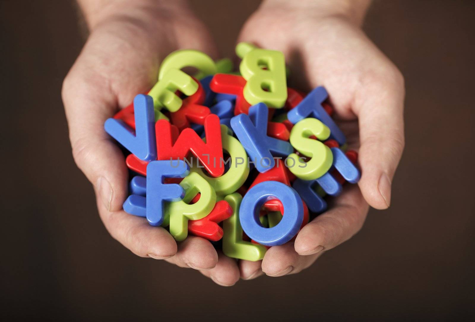 Man holding colorful plastic letters in his hands. Very short depth-of-field.