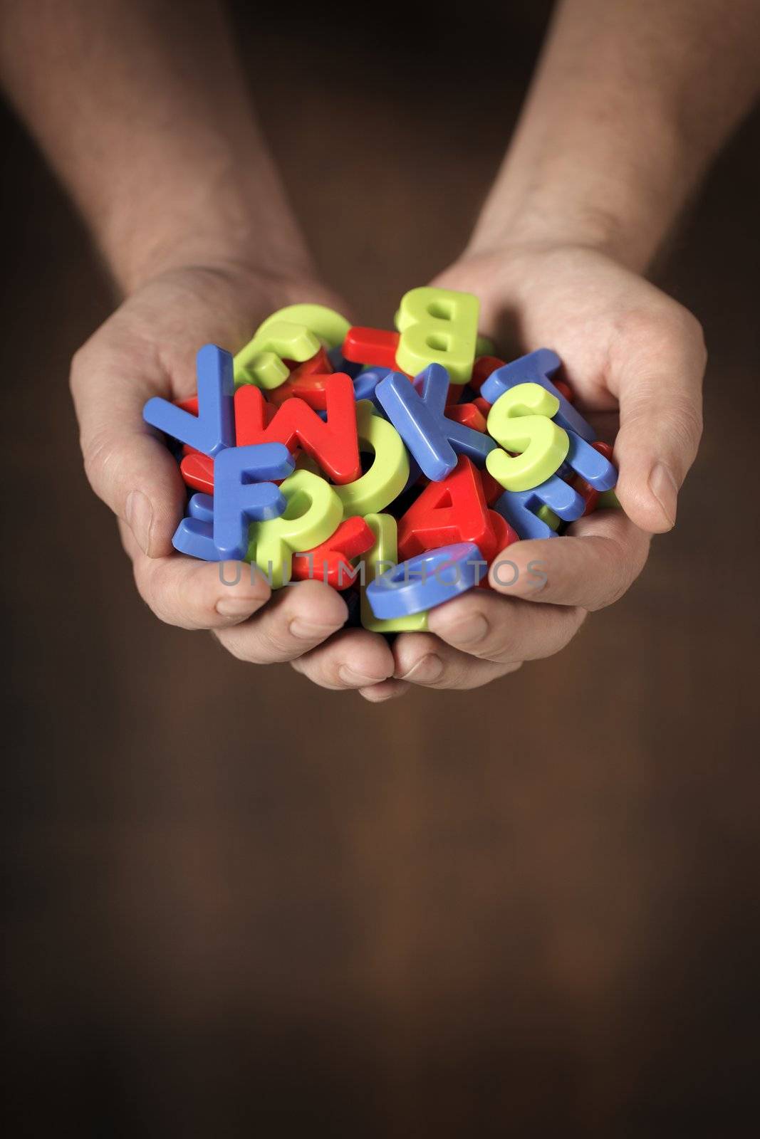 Man holding colorful plastic toy letters in his hands