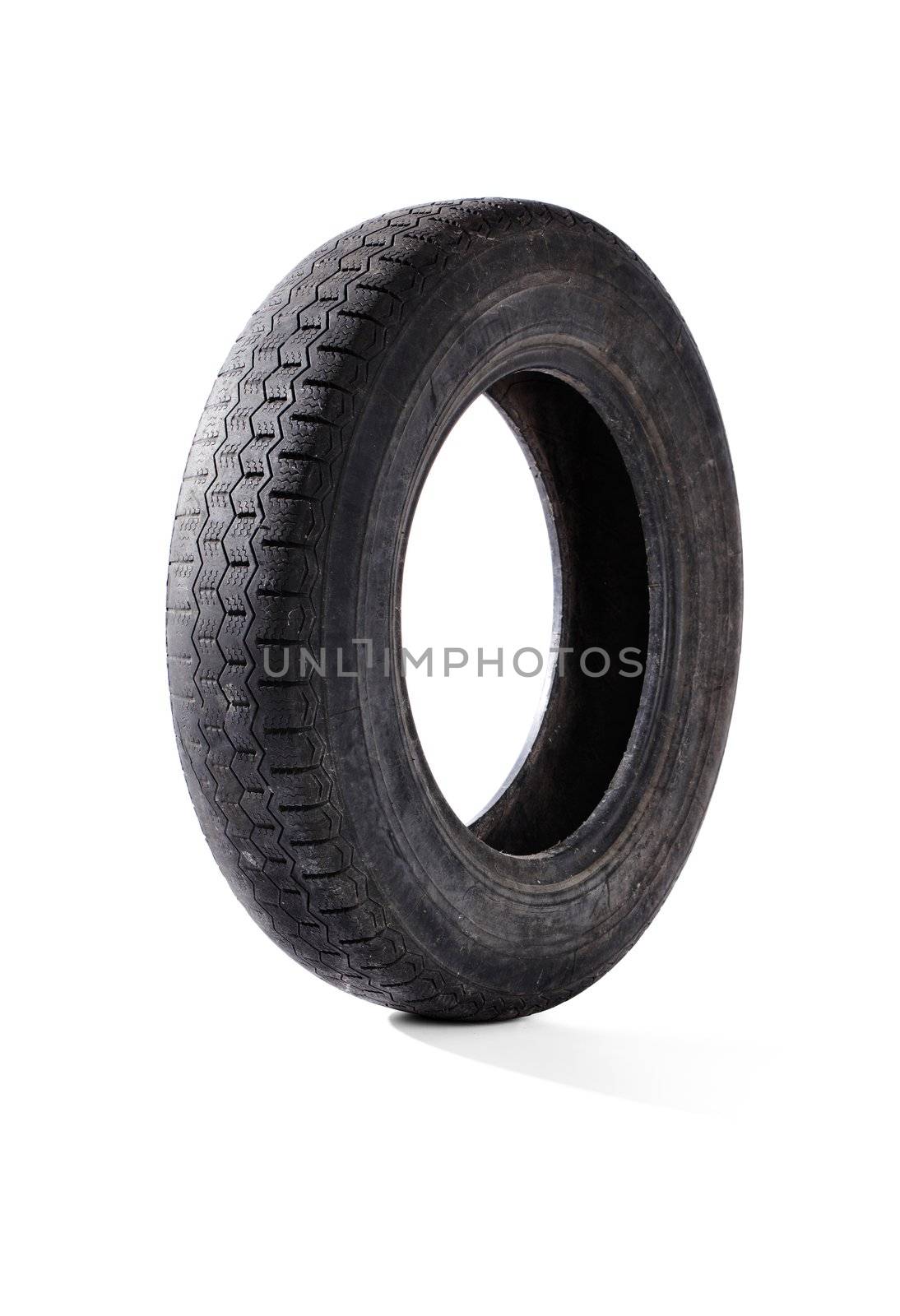 Old worn and weathered car tyre on white with natural shadow