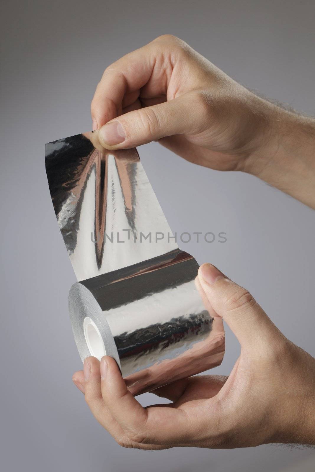 Man holding a roll of adhesive aluminum foil tape in his hands.