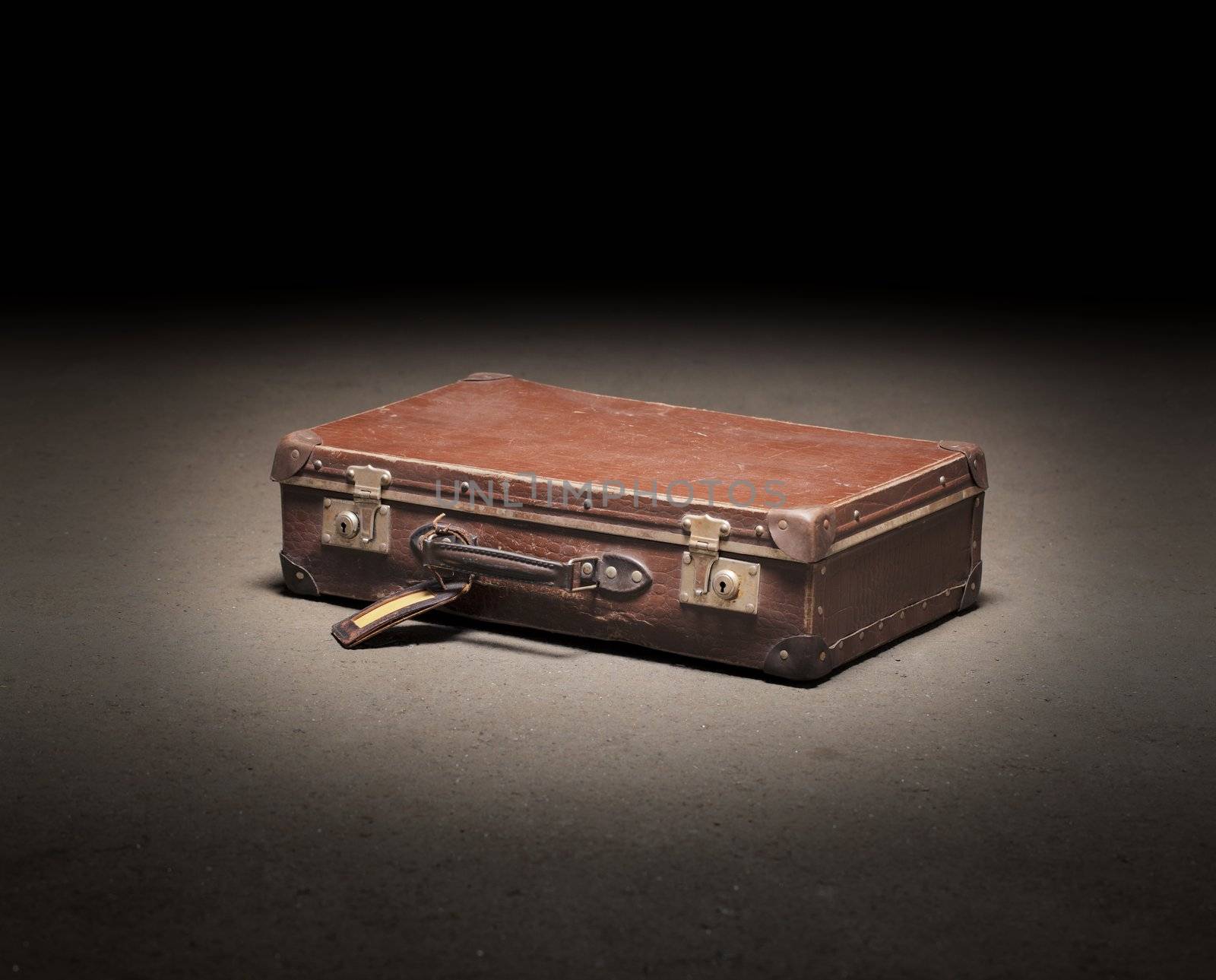 Old brown suitcase on dirty concrete floor