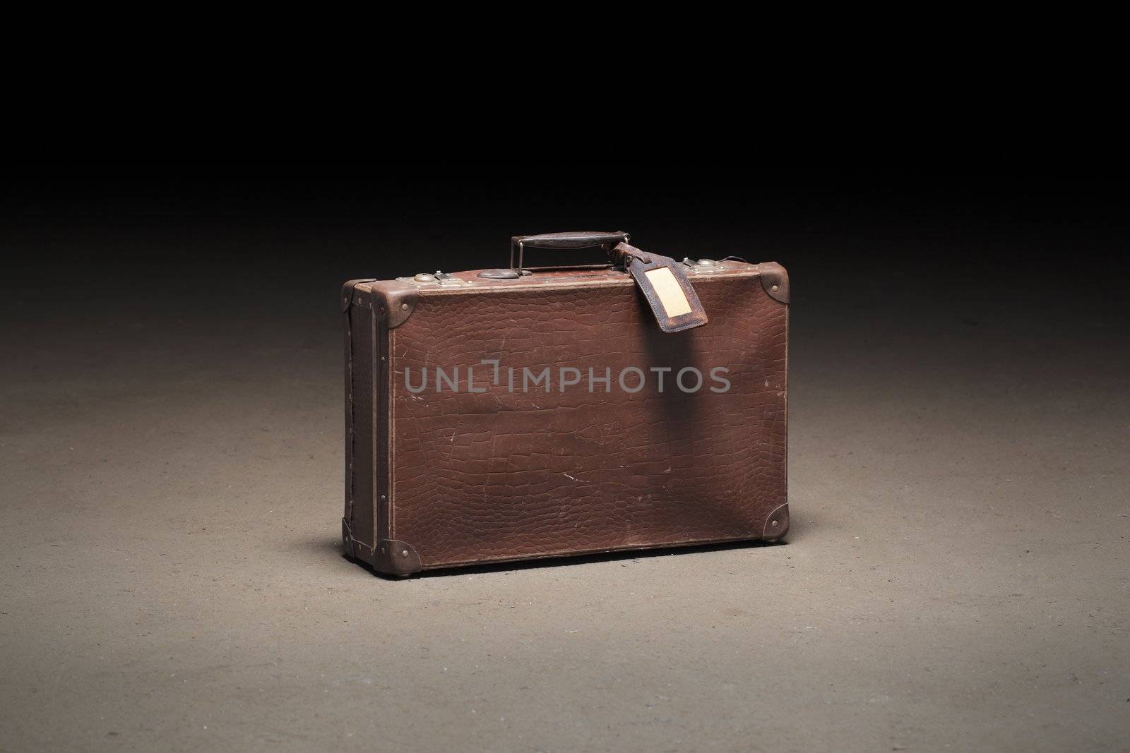 Old brown suitcase abandoned on dirty concrete floor