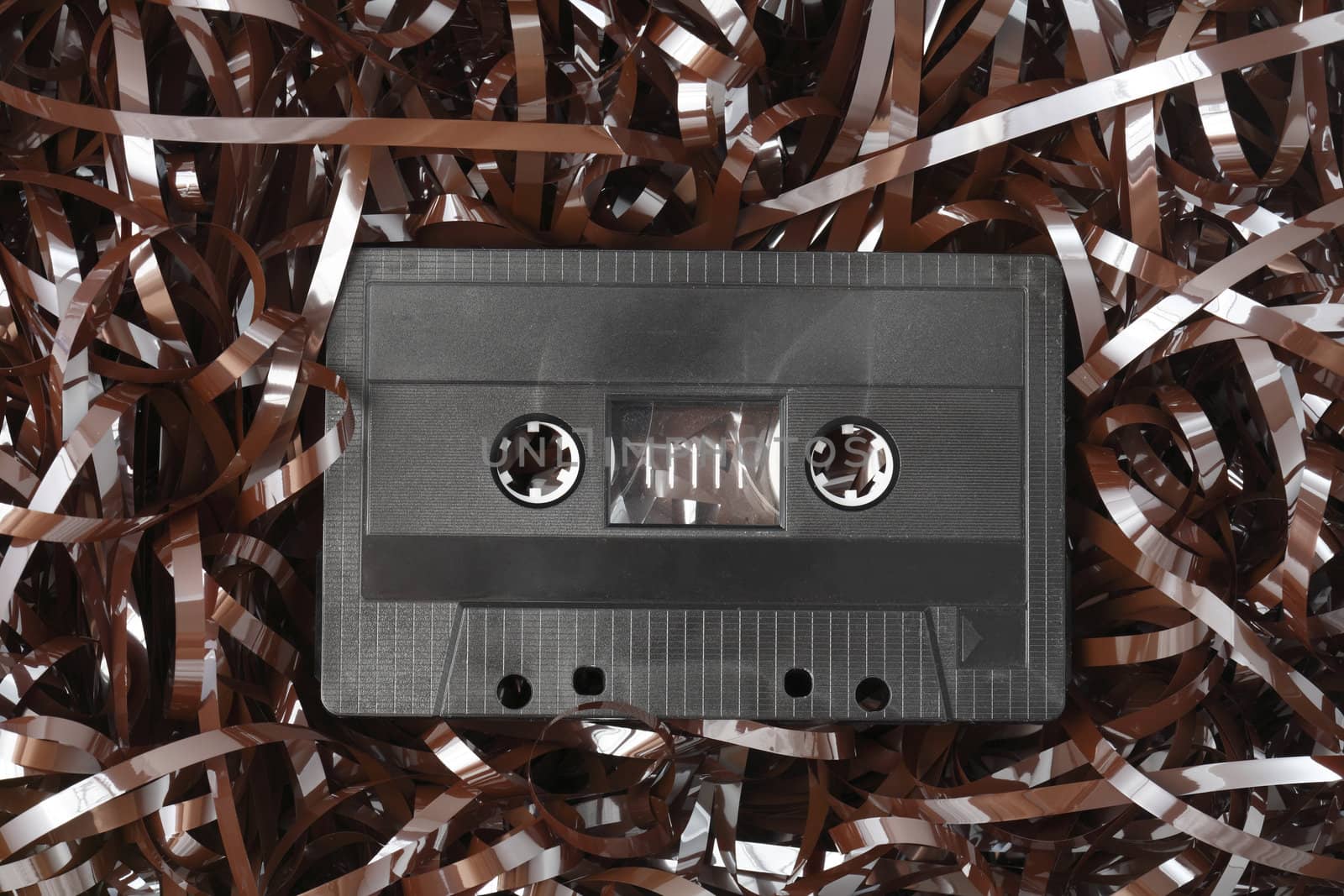 Old black audio C-cassette and tangled tape