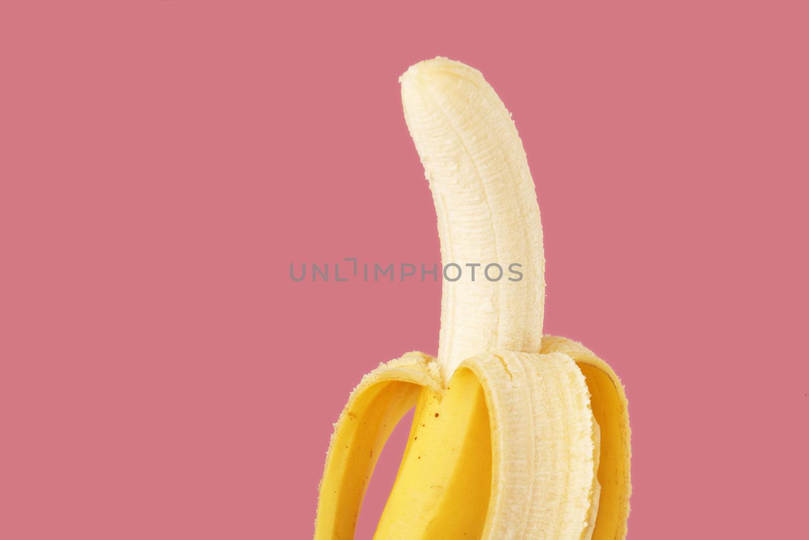A banana ready for eating on pink background