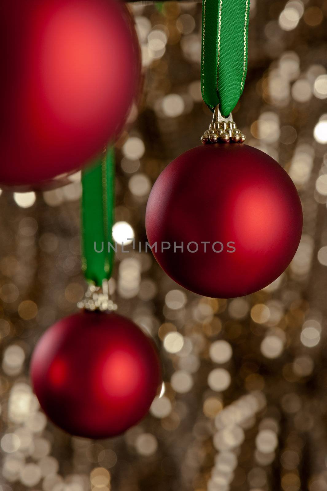 Three red Christmas baubles in front of a gold glitter background for Christmas or decoration