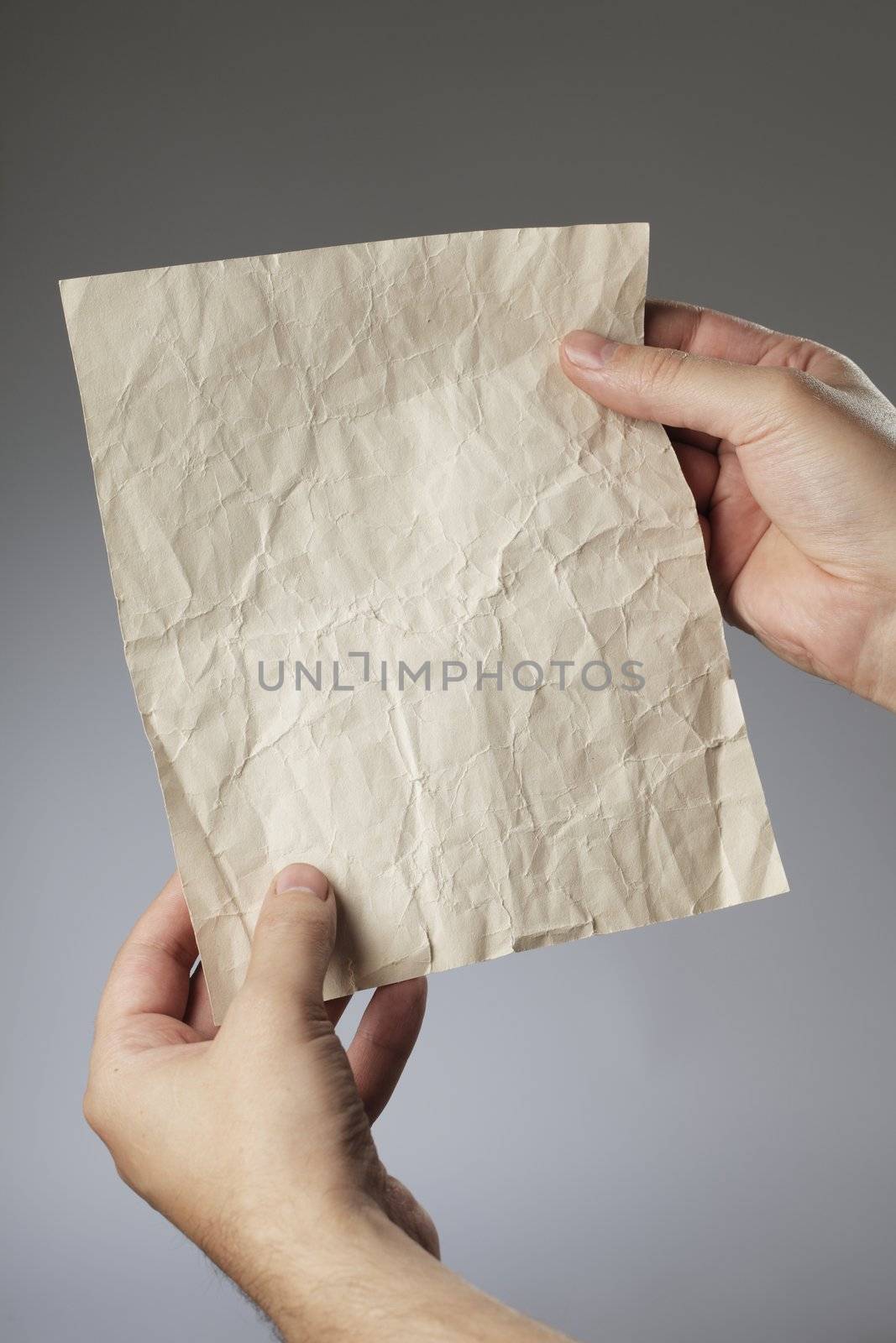 Man holding an old crumpled paper in his hands.