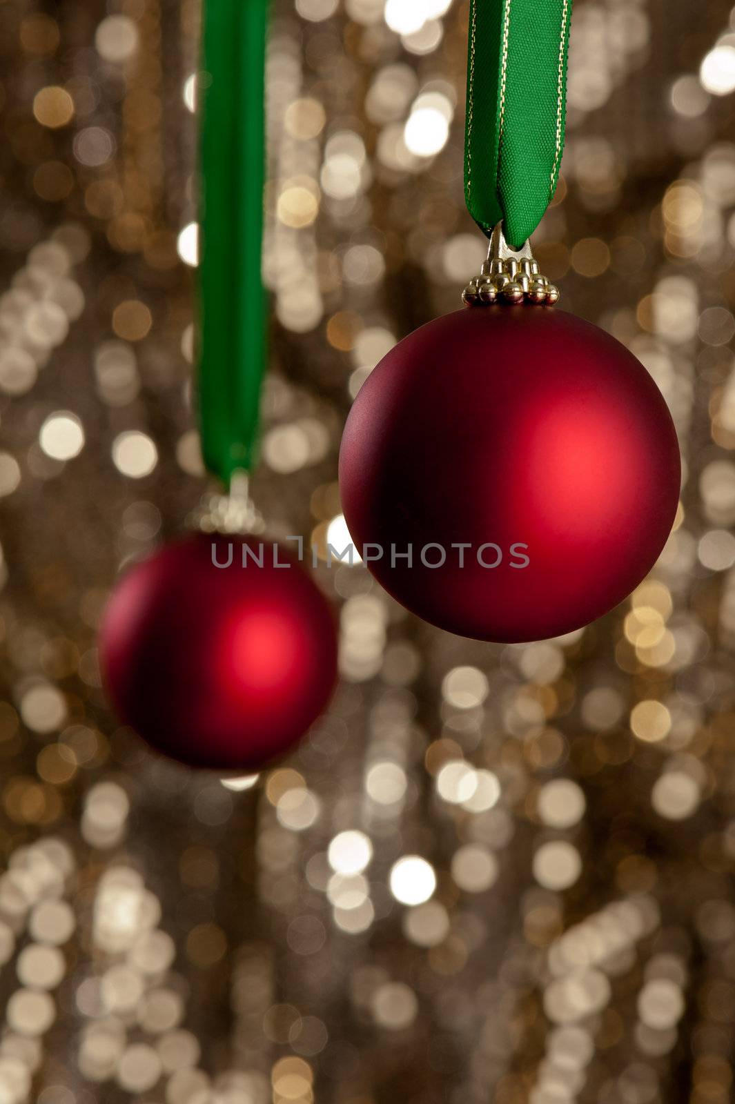 Two red Christmas baubles in front of a gold glitter background for decoration purpose or Christmas use