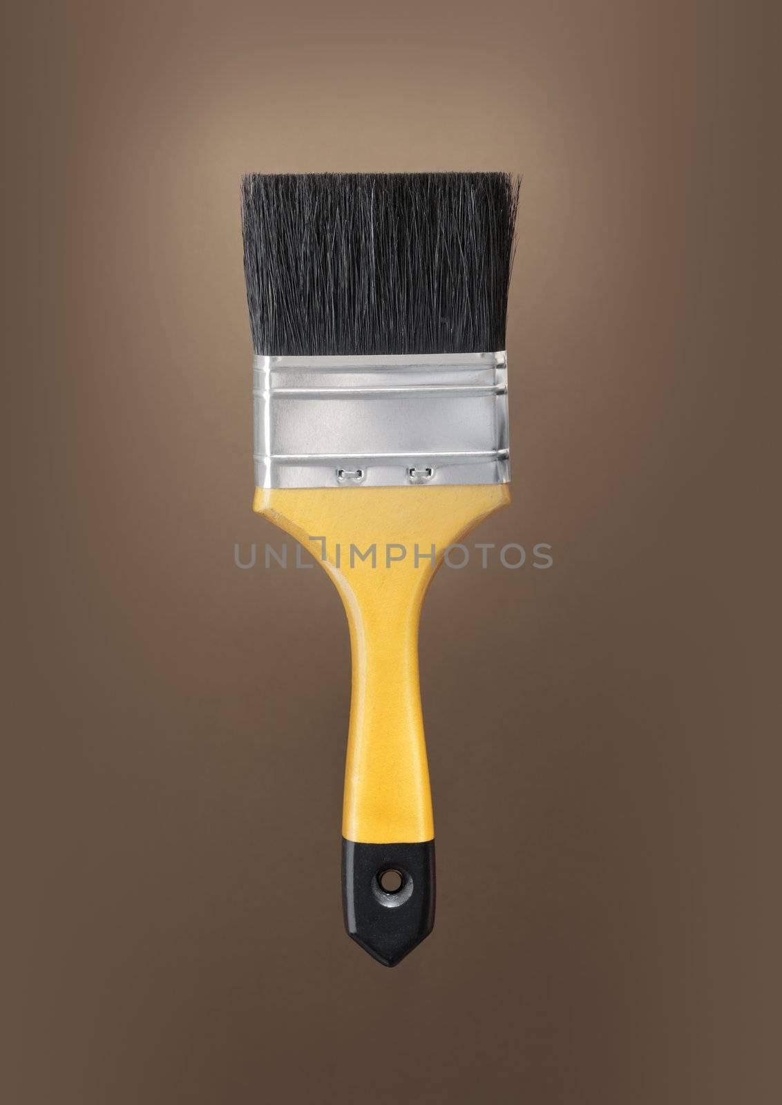 Yellow paint brush on brown background