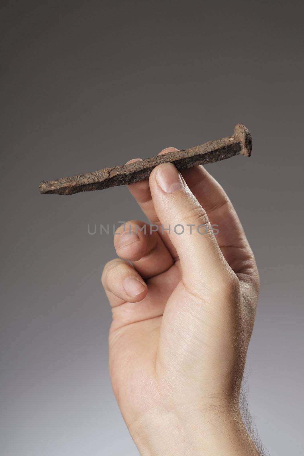 Man holding an old rusty nail in his hand