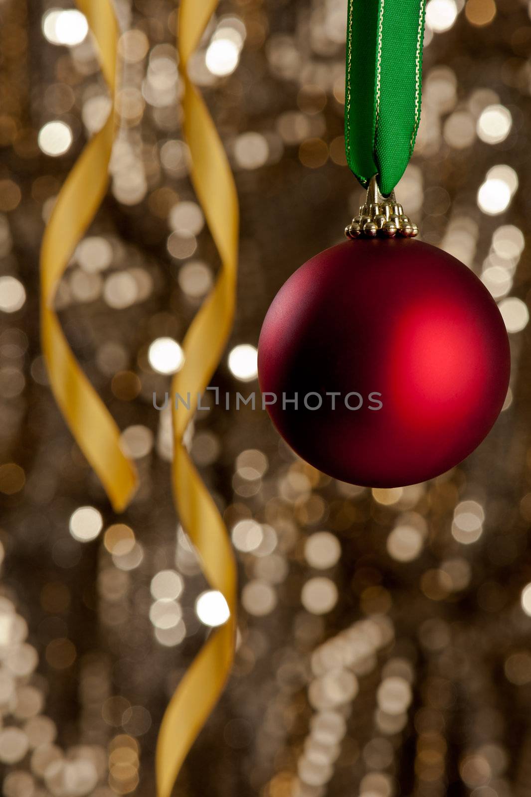Single red Christmas bauble in front of a gold glitter background for Christmas issues